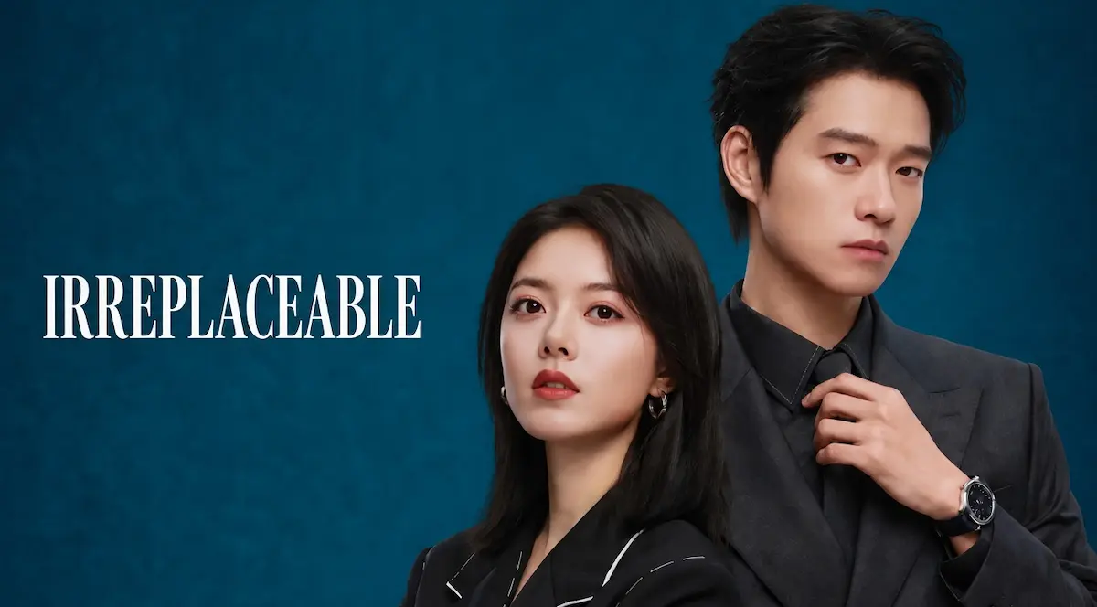 A woman in a black blazer and a man in a dark suit adjusting his tie standing in front of a teal blue background with white serif title text reading Irreplaceable