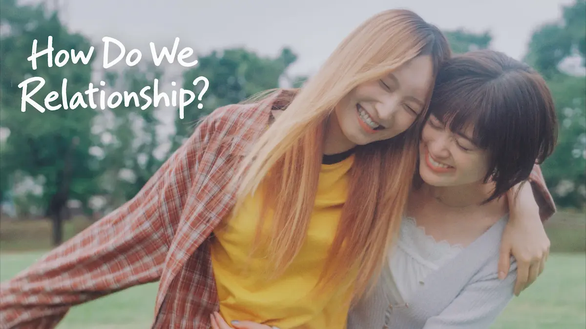 Two young women smiling and hugging outdoors in a park with title text How Do We Relationship?