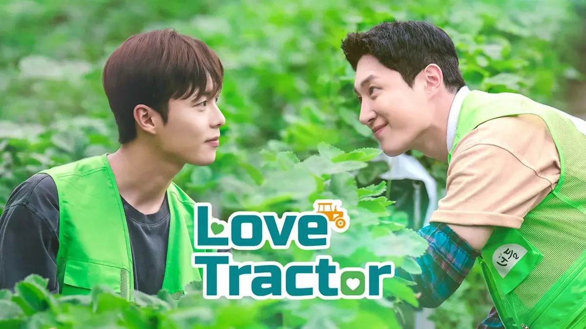 Two young men wearing green vests looking at each other in a green farm field